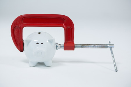 Clamp cutting piggy bank on white backgroundの写真素材