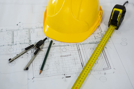 Close-up of blueprint with tape measure, pencil, thumbscrew compasses and hard hatの写真素材