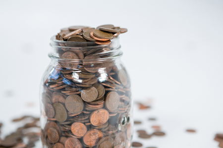 Glass jar full of coins on white background