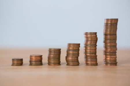 Stack of coins on table against white backgroundの写真素材