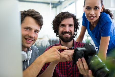 Portrait of team of graphic designers holding camera at office