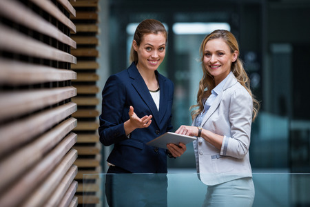 Portrait of business colleagues using digital tablet in office lobbyの写真素材