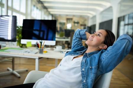 Female business executive relaxing on a chair in officeの写真素材