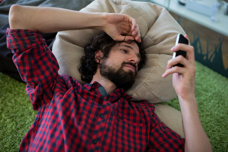 Man text messaging on mobile phone at the officeの写真素材