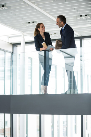 Business colleagues interacting with each other in office corridorの写真素材