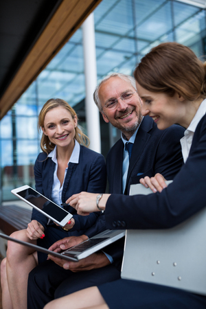 Businesspeople discussing over laptop and digital tablet in office premisesの写真素材