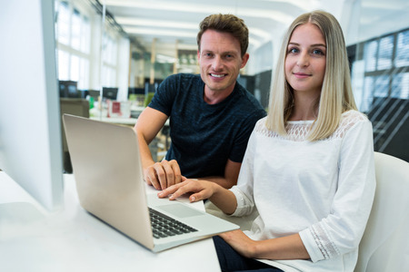 Graphic designers working over laptop at desk in officeの写真素材