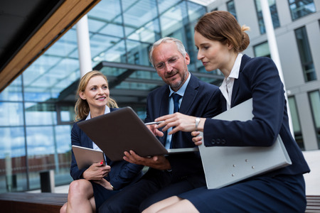 Businesspeople discussing over laptop in office premisesの写真素材