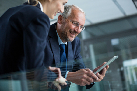 Businessman with colleague using digital tablet in officeの写真素材