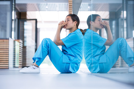 Worried nurse sitting in hospital corridorの写真素材