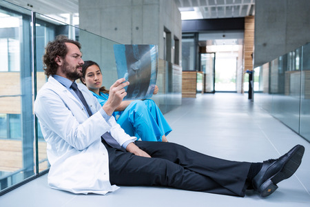 Stressed doctor and nurse examining X-ray report in hospital corridorの写真素材