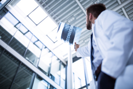 Doctor examining X-ray report in hospitalの写真素材