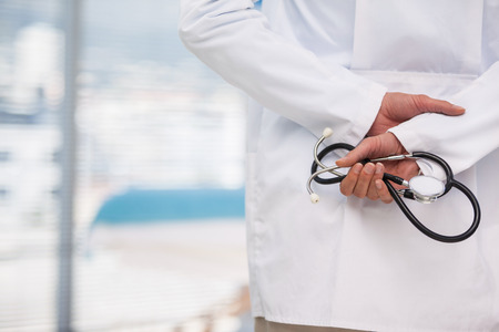 Mid-section of doctor holding stethoscope in hospitalの写真素材