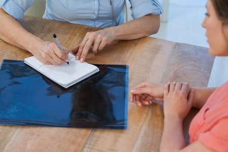 Doctor writing a prescription for her patient in medical office at hospitalの写真素材