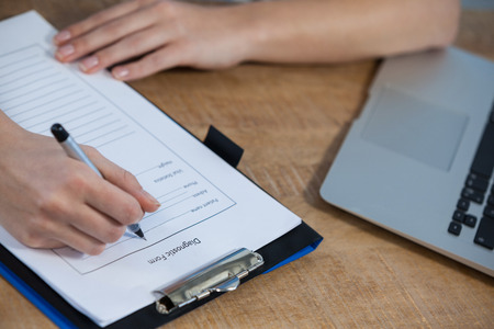 Close-up of doctor's hand writing a medical report in clinic