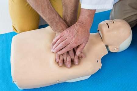 Paramedics training cardiopulmonary resuscitation to man in clinic