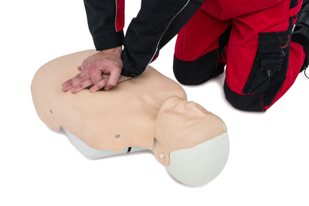 Paramedic practising resuscitation on dummy against white background