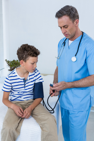 Doctor checking blood pressure of patient in clinicの写真素材