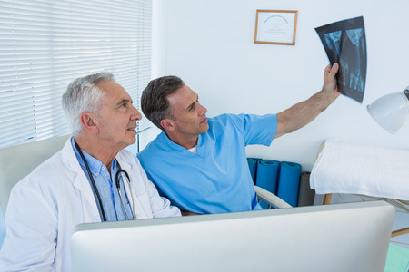 Surgeon and doctor discussing x-ray report in clinic