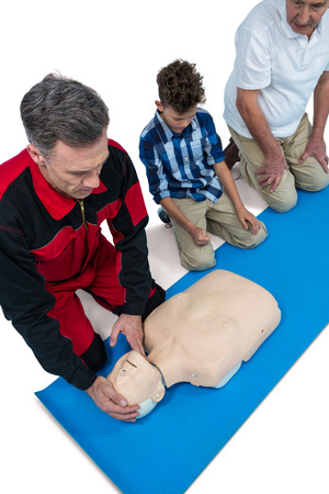Paramedic training cardiopulmonary resuscitation to senior man and boy against white background