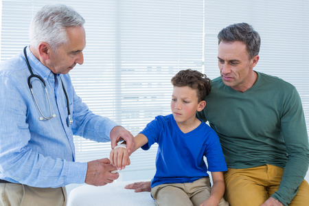 Doctor tying hand band on hand of a patient in clinicの写真素材