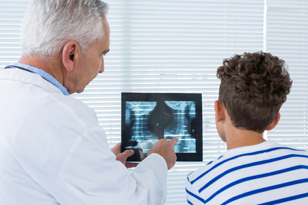 Doctor discussing x-ray report with patient in clinicの写真素材