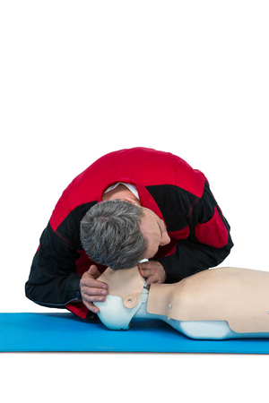 Paramedic practicing resuscitation on dummy against white background
