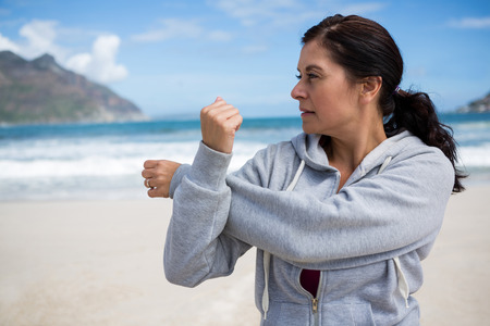 Mature woman performing stretching exercise on beach