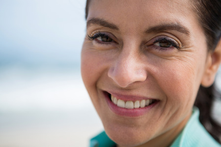 Close-up of smiling woman on beach during winterの写真素材