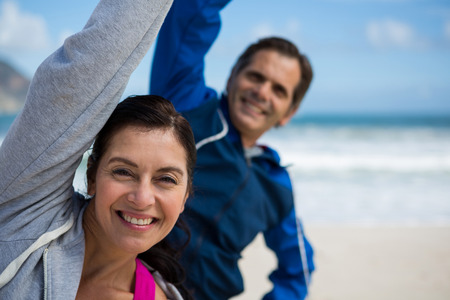Couple performing stretching exercise on beachの写真素材