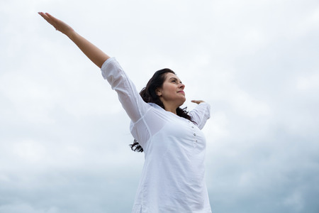 Happy woman standing with arms outstretched on beachの写真素材