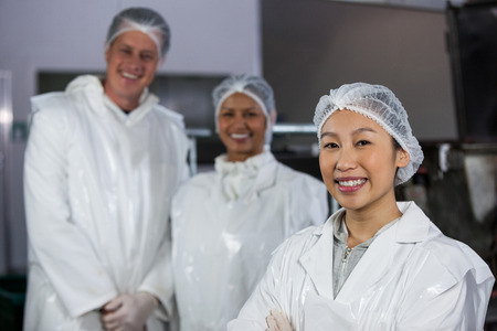 Team of smiling butcher standing in meat factoryの写真素材