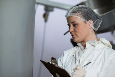 Female butchers maintaining records on clipboard at meat factory