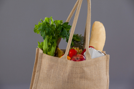 Vegetables and fruits in grocery bag against grey backgroundの写真素材