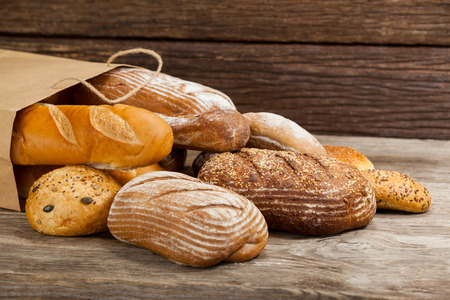 Various bread loaves in bag on wooden background