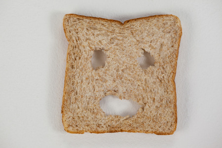 Close-up of a bread slice with smiley face on white backgroundの写真素材