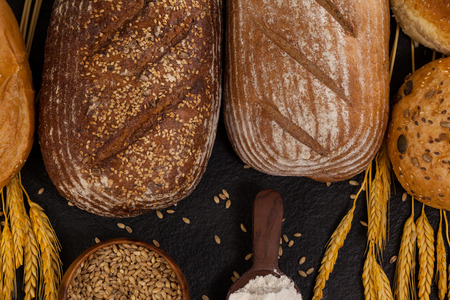 Close-up of various bread loaves with flour and wheat grains