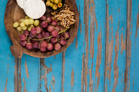 Close-up of cheese, grapes, olives and walnuts in wooden bowlの写真素材