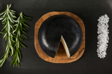 Close-up of black cheese with rosemary and salt on serving trayの写真素材