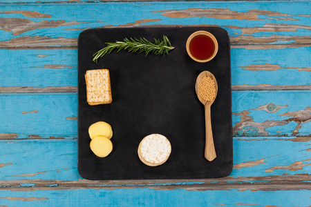 Close-up of rosemary, cheese and biscuits with spices on slate board