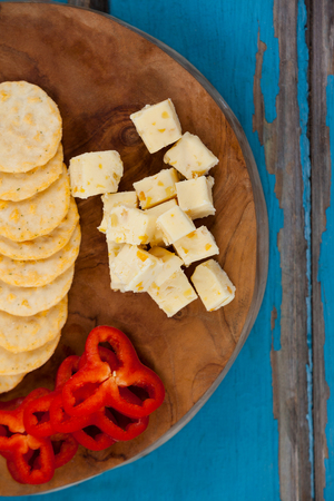 Close-up of cheese cubes, capsicum and biscuits on wooden board