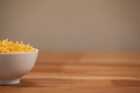 Grated cheese in a bowl on wooden tableの写真素材