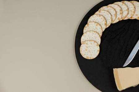 Close-up of slice of cheese with crispy biscuits and knife on chopping boardの写真素材