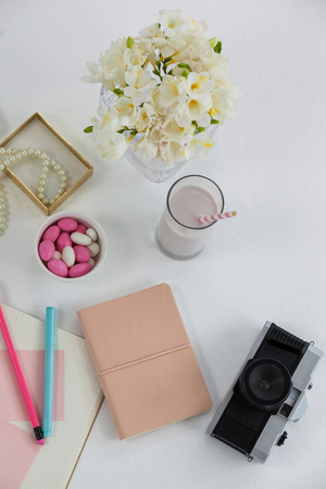 Flowers, diary, camera, glass and pearl necklace on white backgroundの写真素材