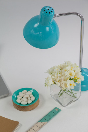 Table lamp, flowers, pebbles and ruler on white backgroundの写真素材