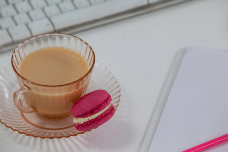Cup of tea with a french macaroon on work deskの写真素材