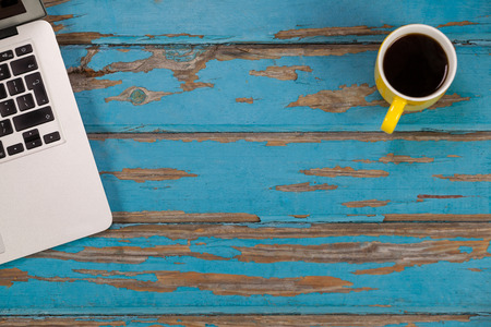 Coffee mug and laptop on old wooden plankの写真素材