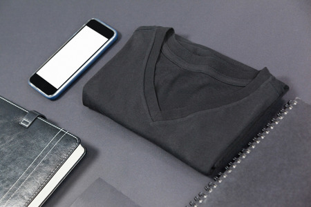 Folded t-shirt, smartphone, diary, card and note pad on grey backgroundの写真素材