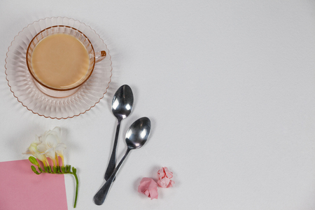 Cup of tea, spoons, blank page, paper balls and flower on white backgroundの写真素材
