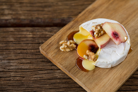 Brie cheese, with apricot and walnut pieces on serving board over wooden tableの写真素材
